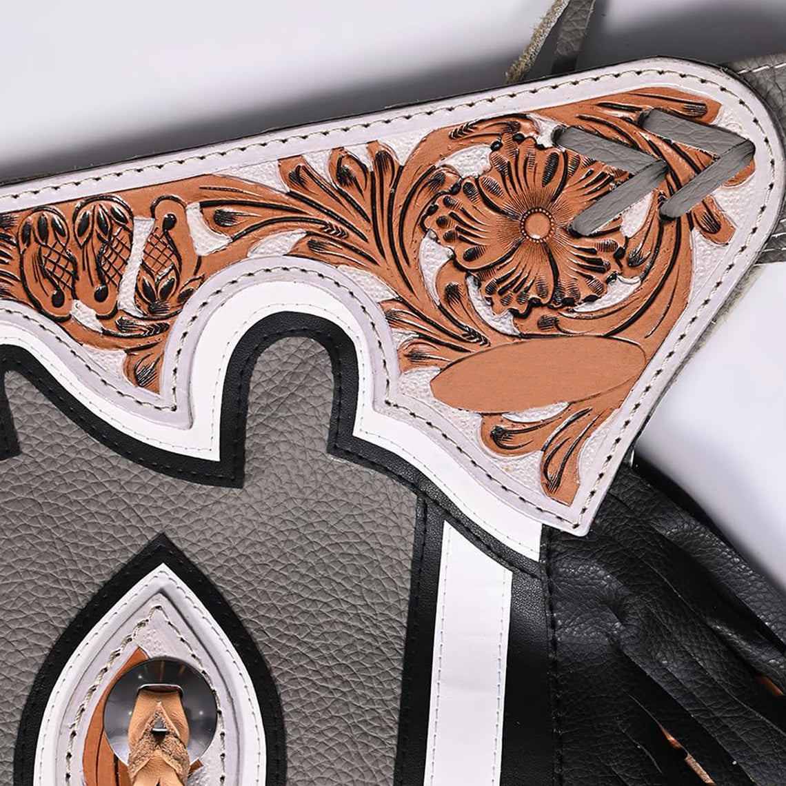 Close up of floral tooled yoke on gray rodeo chaps