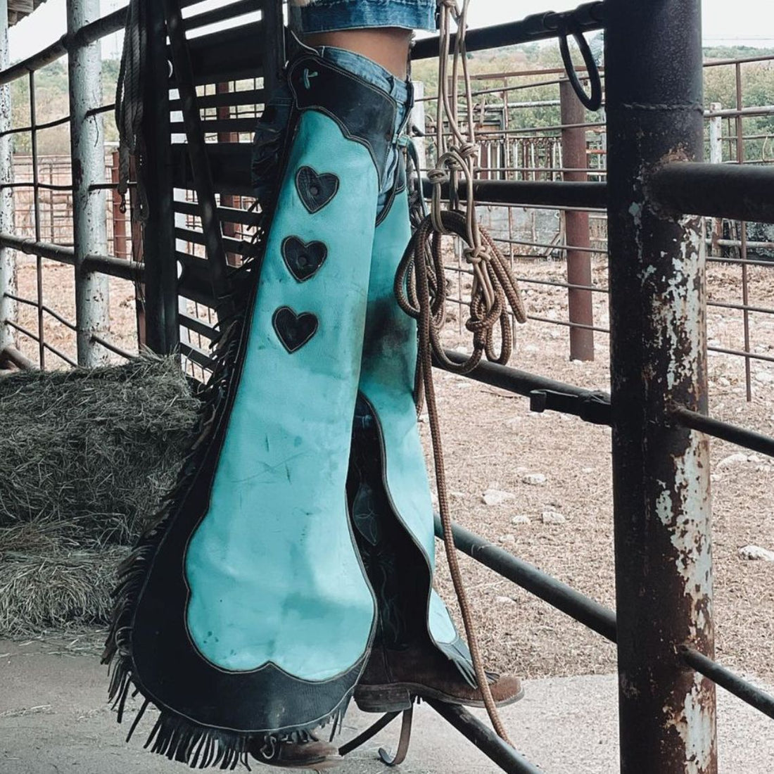 Women’s turquoise and black western chaps with heart patch front view